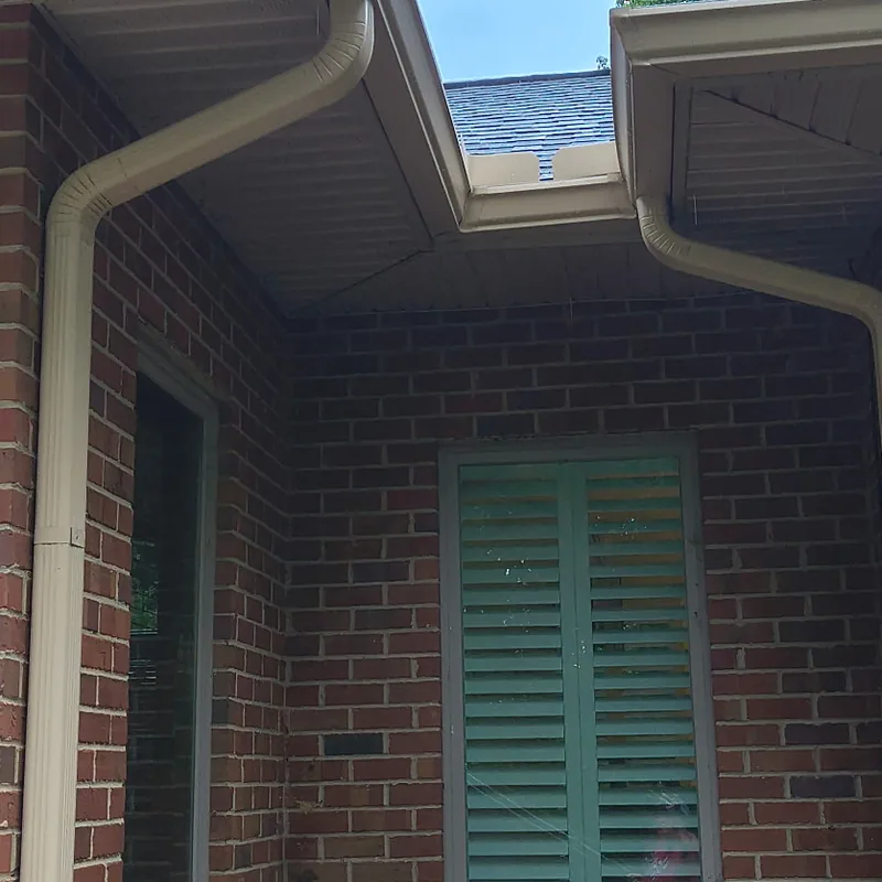 Seamless gutters and downspouts along the rooflines of a red brick home