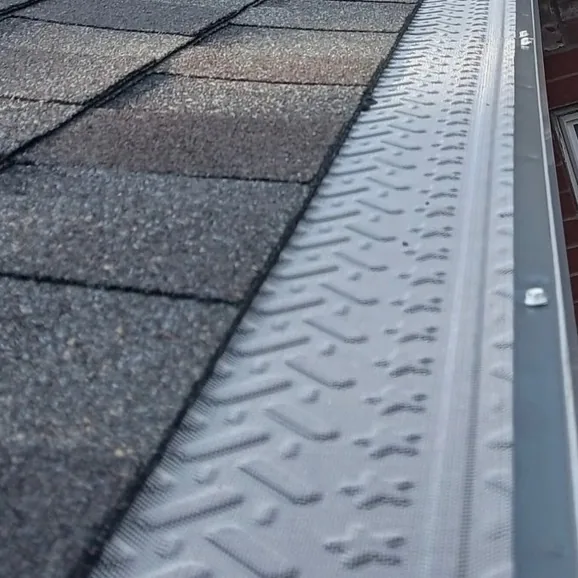 Close-up of an embossed micro-mesh gutter guard installed along a shingle roof edge