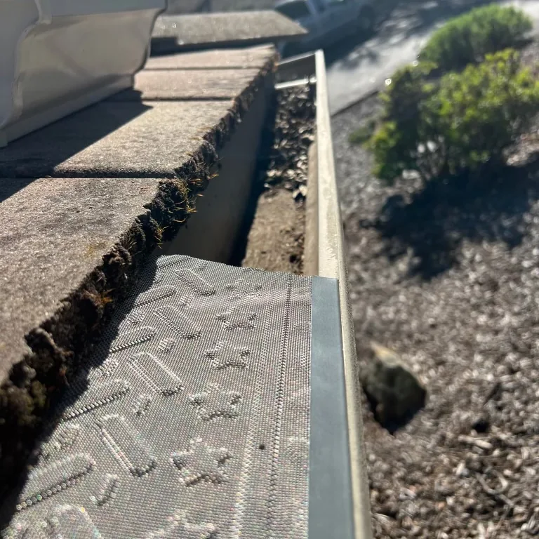Micro-mesh gutter guard being installed over a gutter that was packed with roof grit and debris