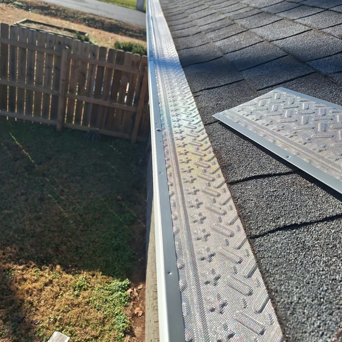 Gutter guard panels being installed along a shingle roofline in a Middle Tennessee neighborhood