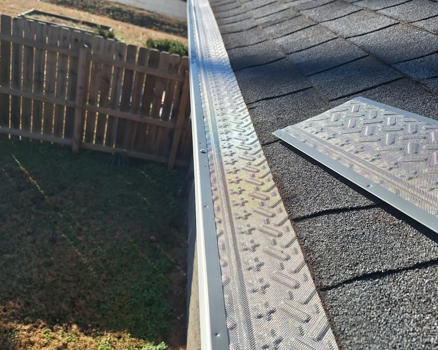 Gutter guard panels being installed along a shingle roofline in a Middle Tennessee neighborhood