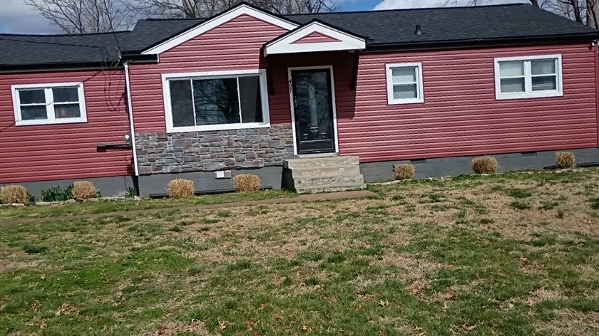 Single-story home with red vinyl siding, stone accents, and a new black architectural shingle roof