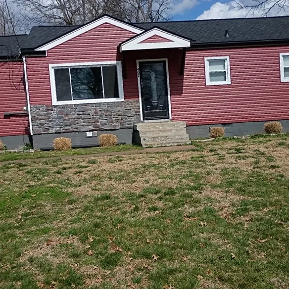 Single-story home with red vinyl siding, stone accents, and a new black architectural shingle roof