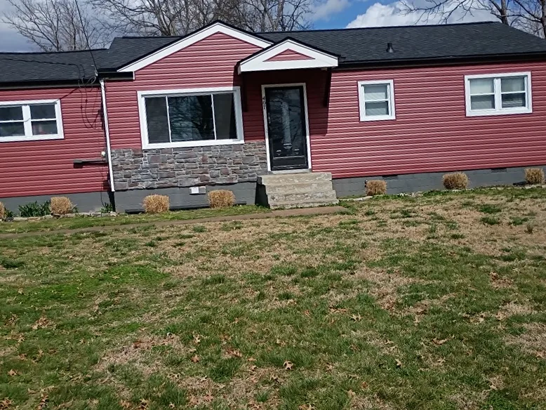 Single-story home with red vinyl siding, stone accents, and a new black architectural shingle roof