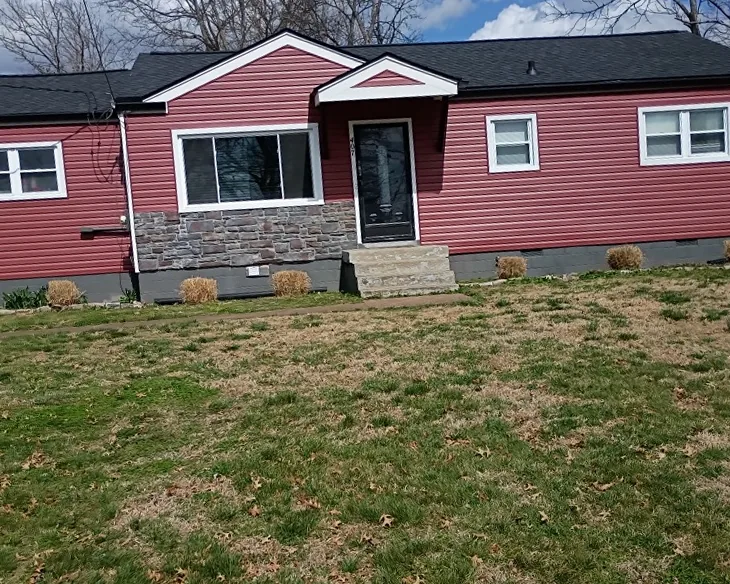 Single-story home with red vinyl siding, stone accents, and a new black architectural shingle roof